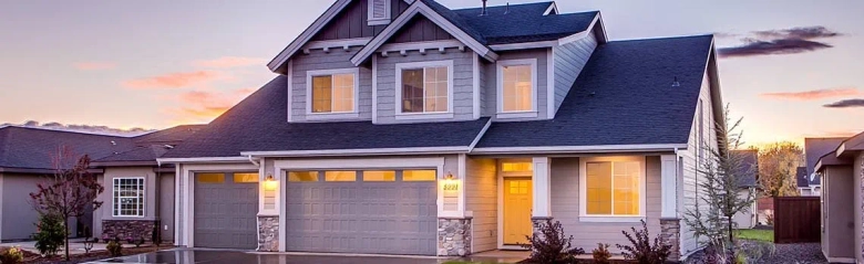 Twilight view of a modern two-story house with a double garage and a lit entrance.